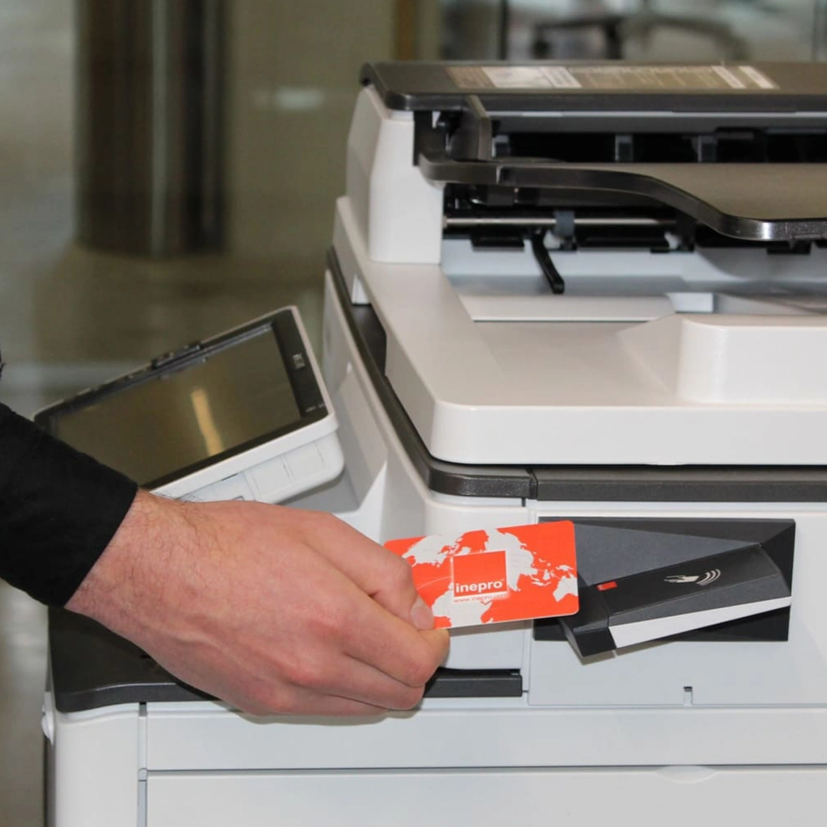 Pessoa aproximando um cartão de identificação do leitor RFID de uma impressora para liberar seus documentos